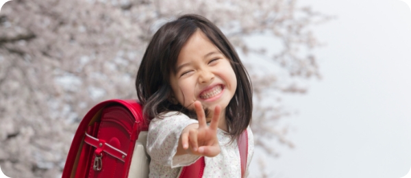 桜の前でピースサインをする女の子の写真
